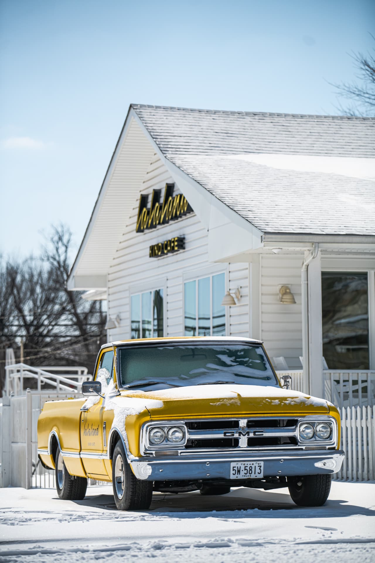 Yellow vintage GMC truck outside Lala Land Kind Cafe in Texas snow