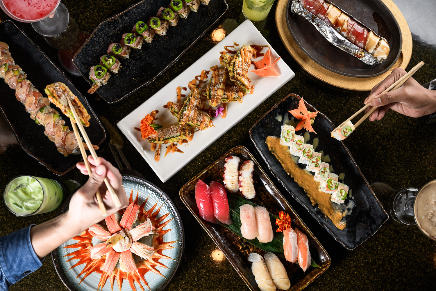 Overhead sushi spread with rolls, nigiri, and cocktails